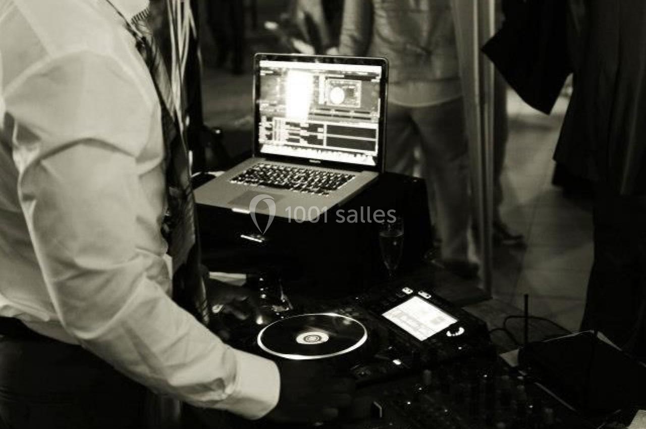 Un DJ mixe de la musique sur une console sous une tente lors d'un événement en soirée.