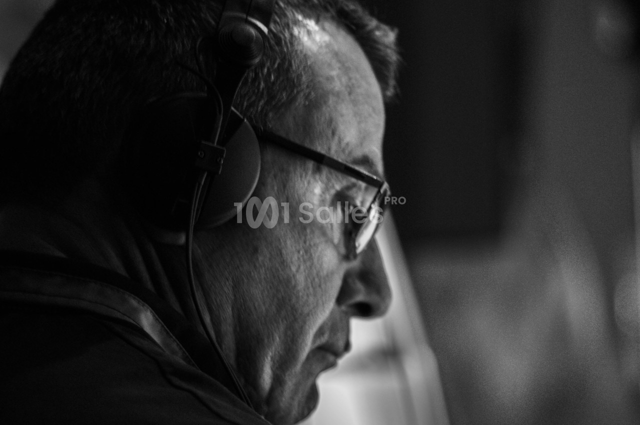 Homme portant un casque audio, vu de profil, concentré dans un environnement sombre en noir et blanc.