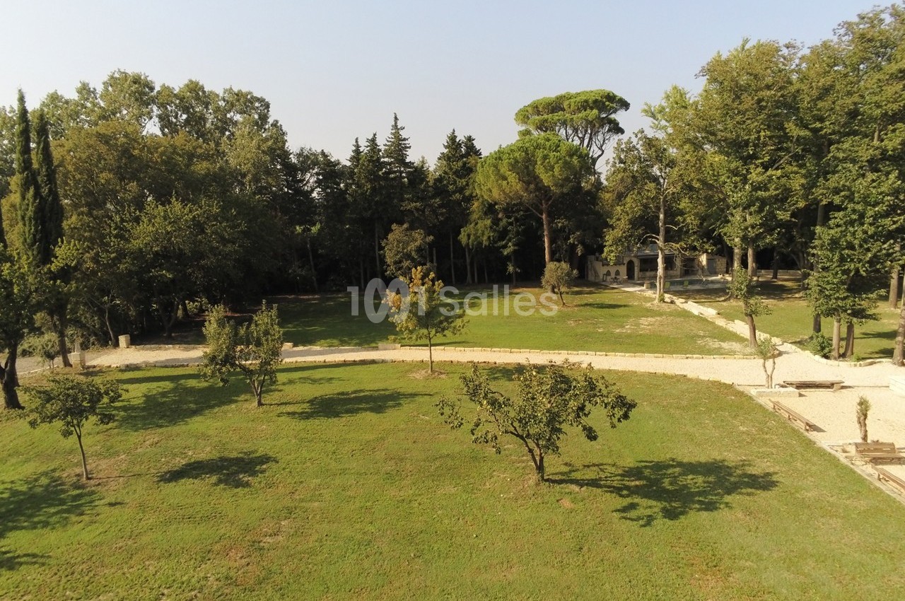 Vue aérienne d'un parc avec pelouse, arbres dispersés et chemins en gravier sous un ciel dégagé.