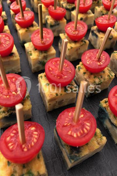 Bouchées de tortilla aux épinards surmontées de demi-tomates cerises, présentées avec des piques en bois.