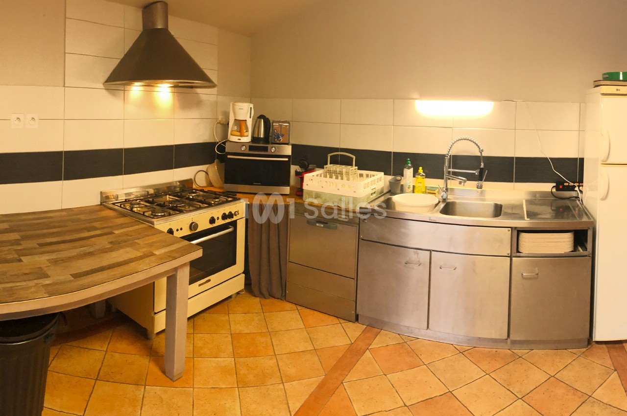 Cuisine équipée avec un plan de travail en bois, un four, une hotte, un évier, un lave-vaisselle et des rangements.