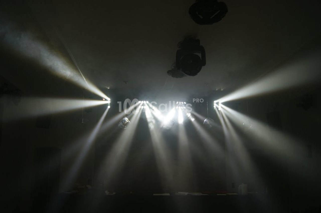 Des projecteurs diffusent des faisceaux lumineux dans une pièce sombre, créant un effet de lumière dramatique.