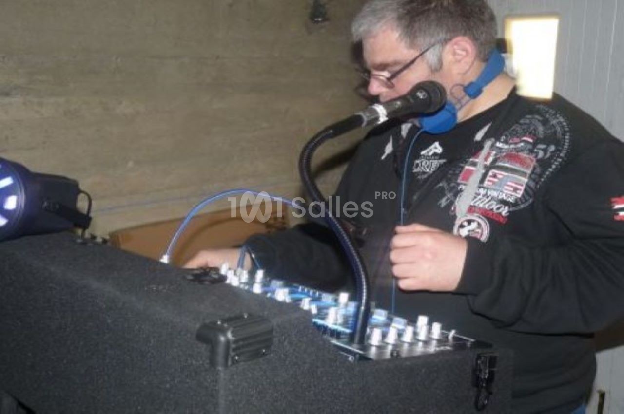 Un homme utilise une table de mixage avec un micro et un casque dans un environnement intérieur.