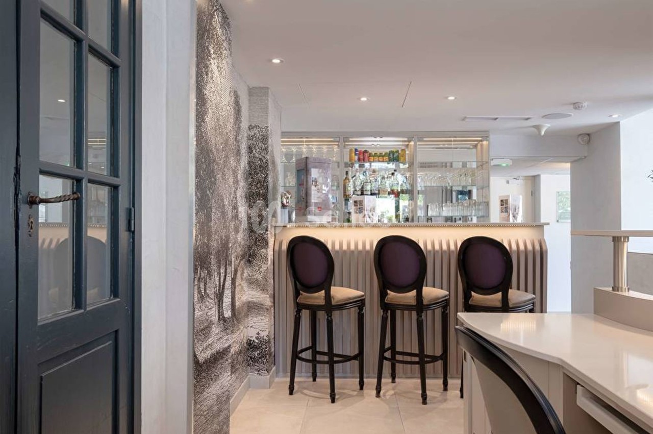 Intérieur d'un bar moderne avec comptoir lumineux, tabourets élégants et décor mural texturé.