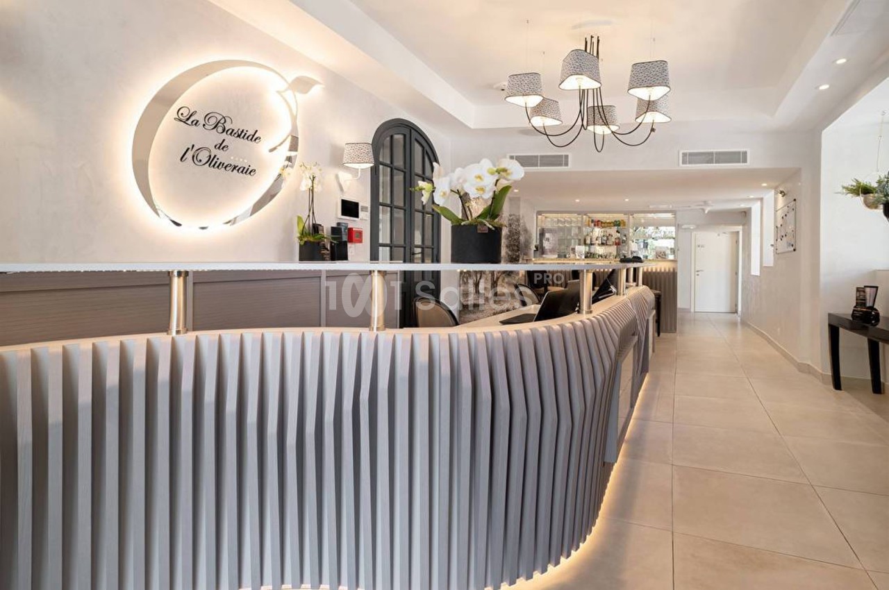 Réception moderne avec comptoir ondulé, éclairage design, orchidées blanches et enseigne murale lumineuse.