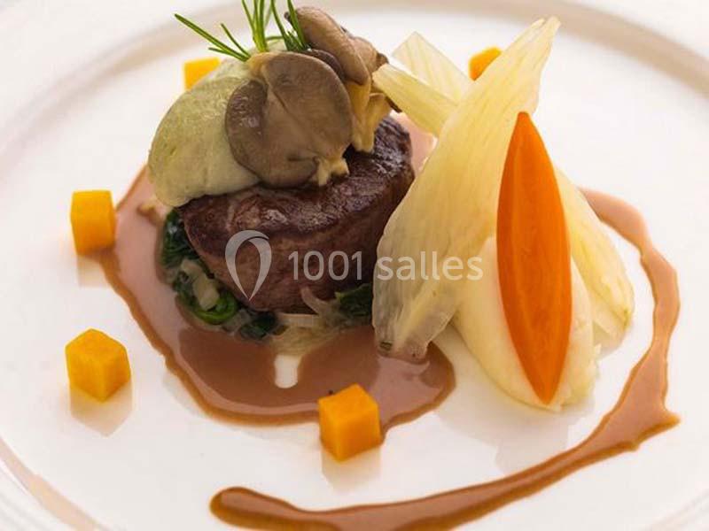 Assiette gastronomique avec viande, purée, légumes variés, champignons et sauce disposés de manière élégante.