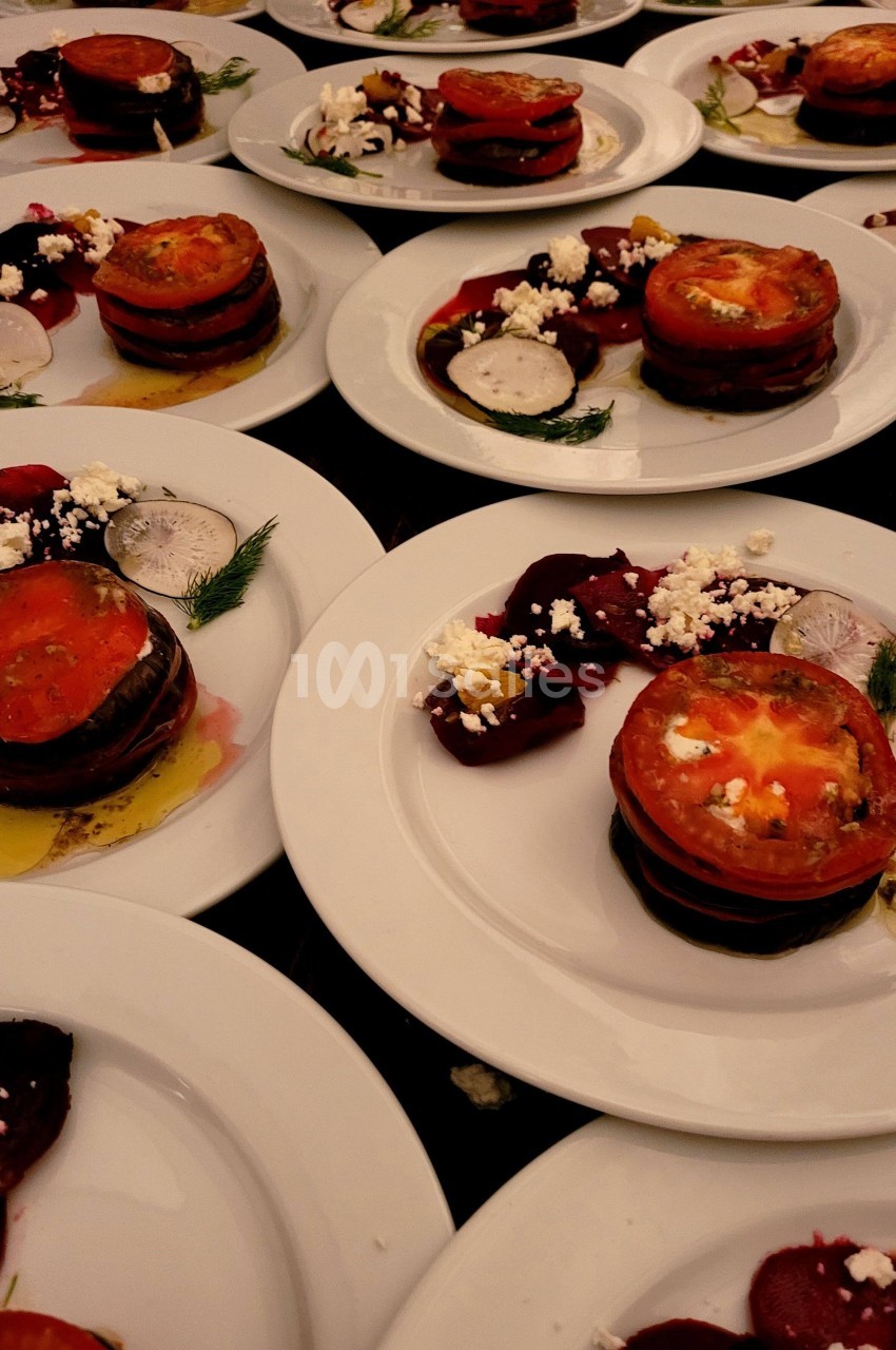 Assiettes de légumes grillés en couches avec tomates, betteraves, fromage émietté et herbes fraîches.