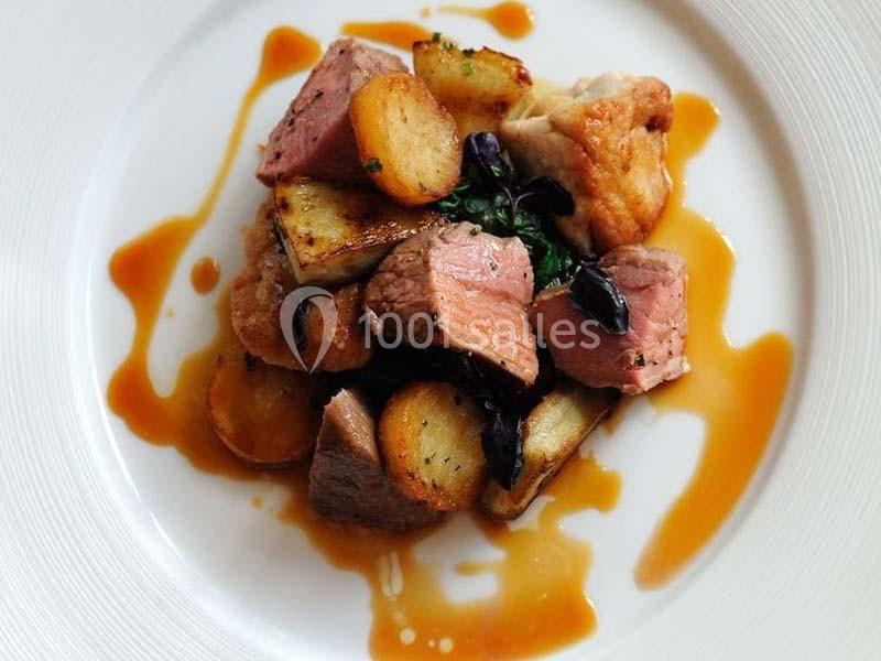 Assiette de viande grillée avec pommes de terre rôties, épinards et sauce, présentée sur une assiette blanche.