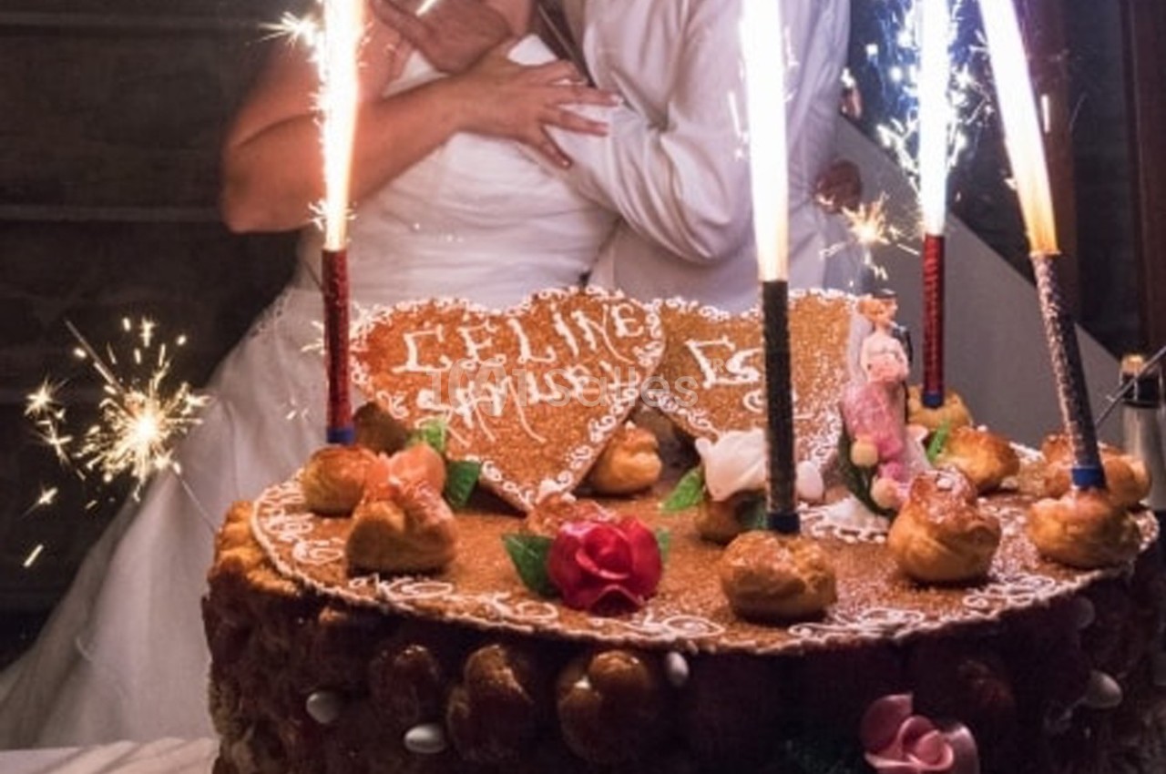 Gâteau de mariage décoré avec des choux, des fleurs en sucre et des cierges magiques allumés.