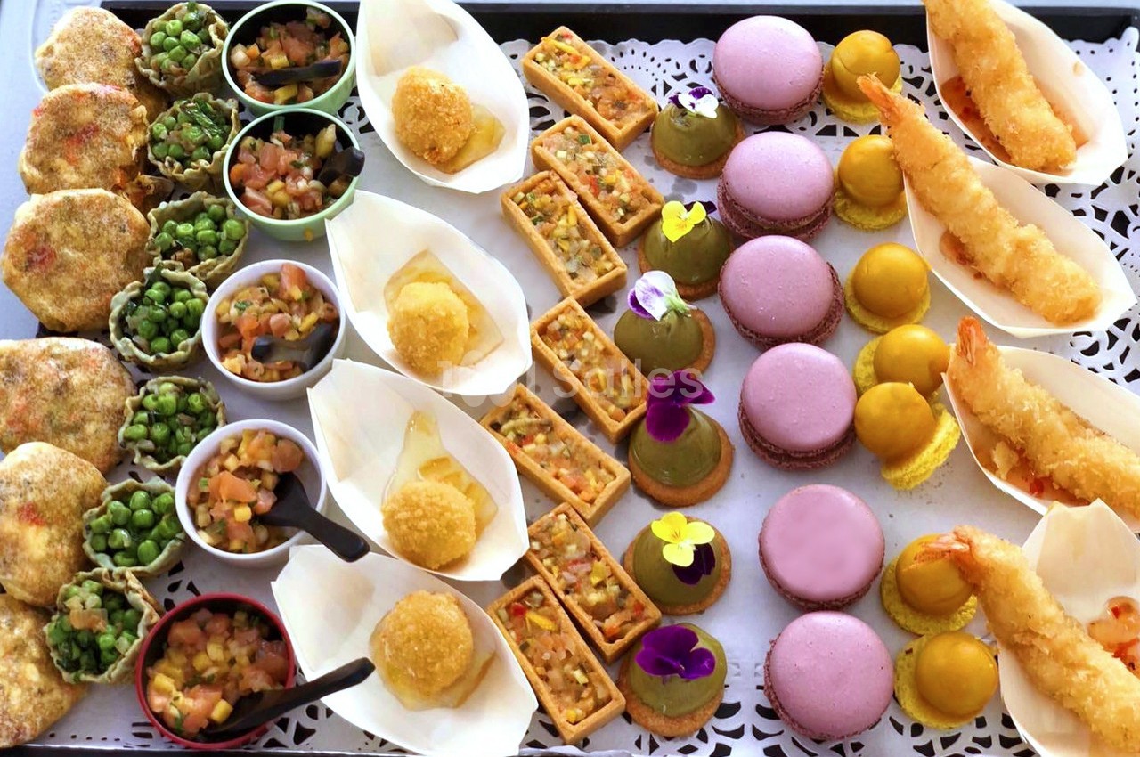Plateau de bouchées variées comprenant macarons, tempuras, verrines, tartelettes et autres amuse-bouches colorés.