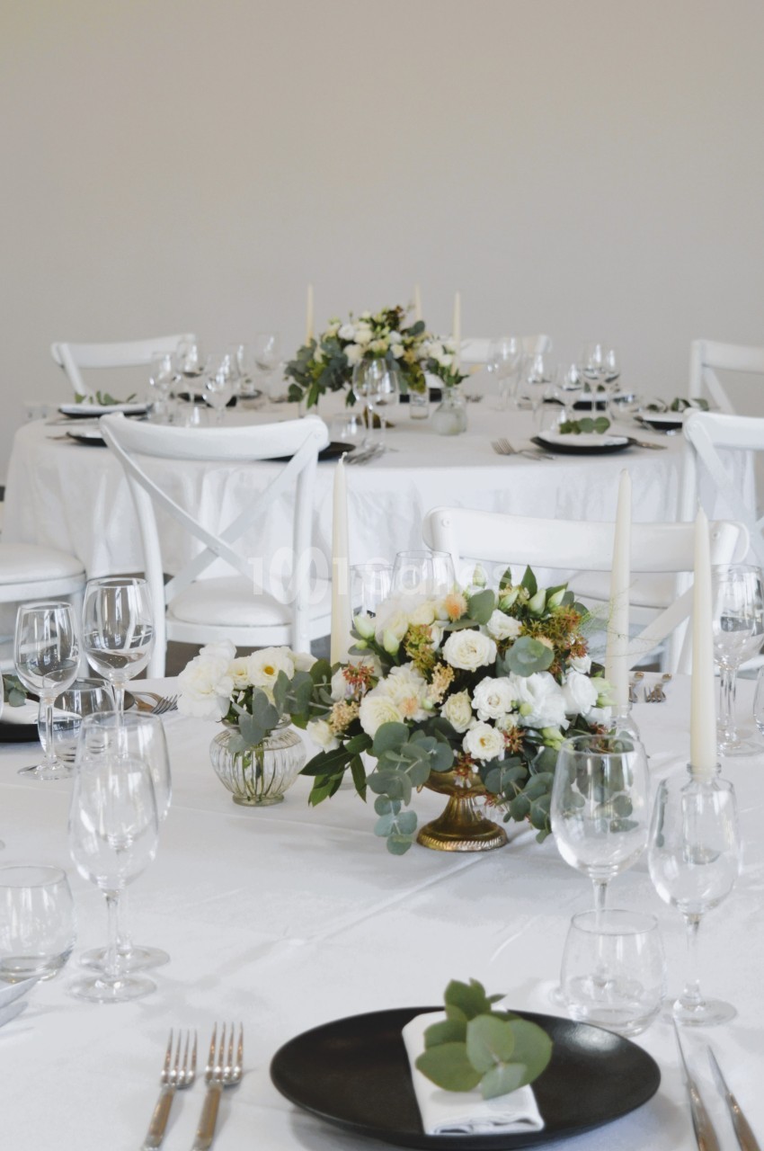 Tables élégamment dressées avec nappes blanches, vaisselle raffinée, bougies et compositions florales.