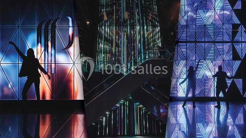 Silhouettes de personnes dans un environnement lumineux et futuriste avec des motifs géométriques et des néons colorés.