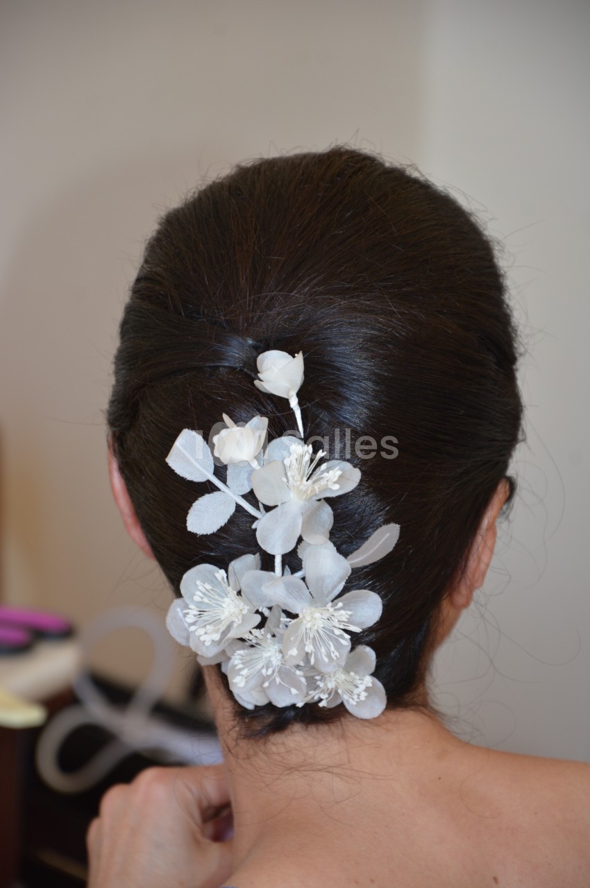 Chignon brun orné de fleurs blanches décoratives en tissu, vu de dos.