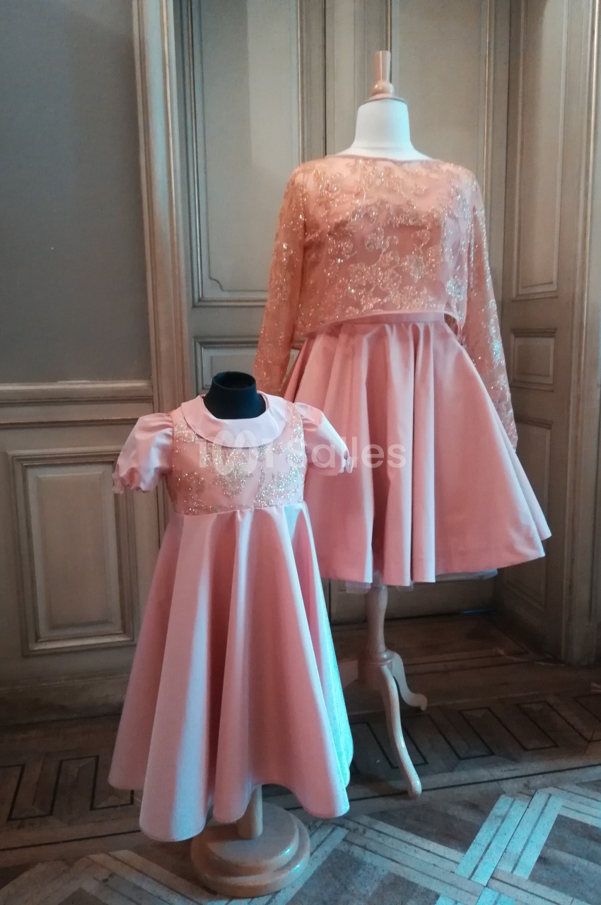 Deux robes roses assorties, une pour adulte et une pour enfant, exposées sur des mannequins dans une pièce élégante.