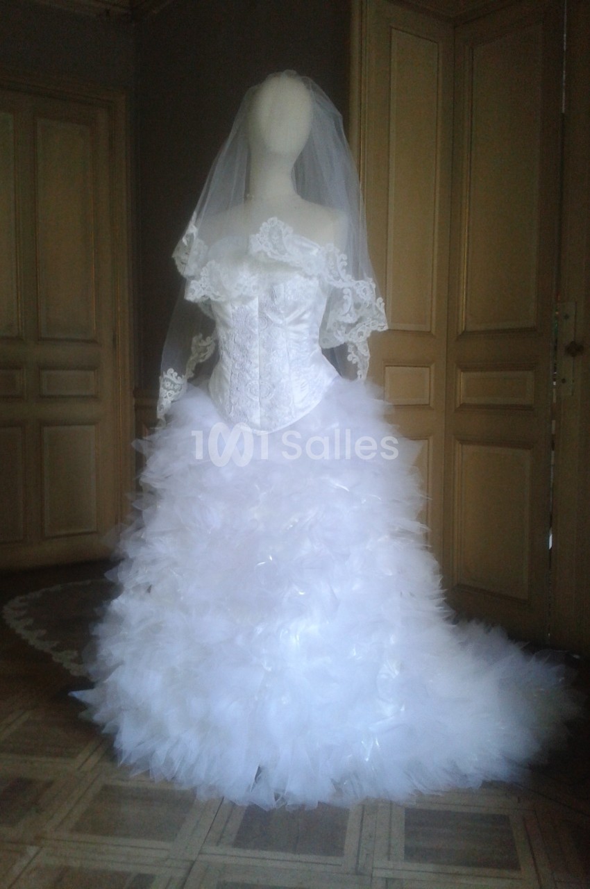Robe de mariée blanche avec corset en dentelle et jupe volumineuse en tulle, présentée sur un mannequin.