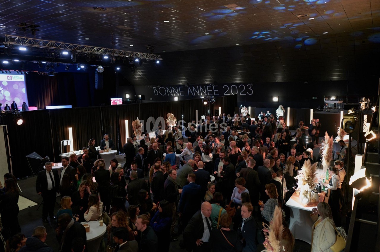 Foule rassemblée dans une salle événementielle décorée, avec l'inscription ’Bonne Année 2023’ en arrière-plan.