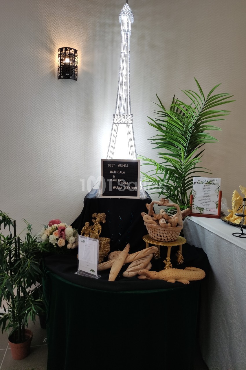 Table décorative avec des pains en forme de baguettes, une tour Eiffel lumineuse et des plantes en arrière-plan.