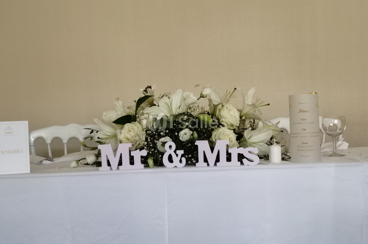 Décoration de table de mariage avec des fleurs blanches, des bougies et une inscription ’Mr & Mrs’.