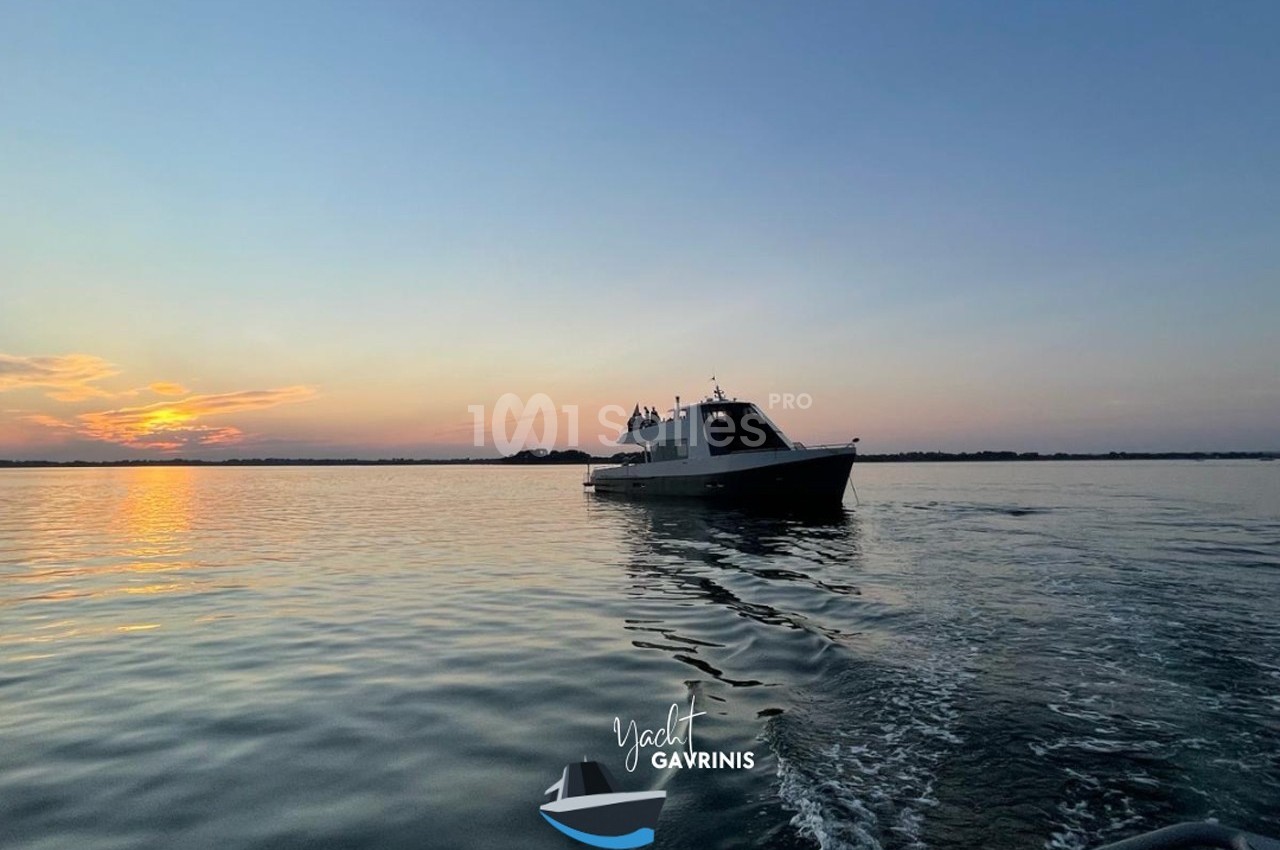 Bateau naviguant sur une mer calme au coucher du soleil, avec des reflets sur l'eau et un ciel dégagé.