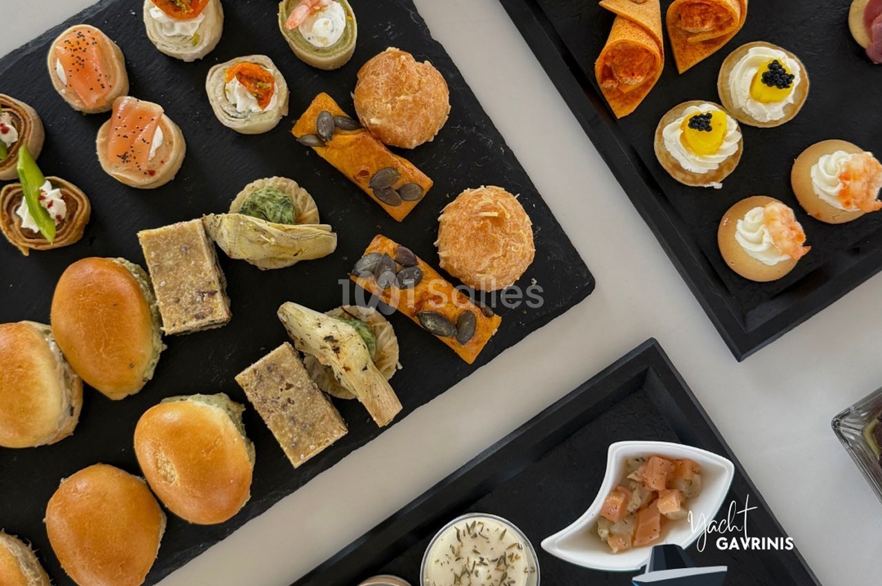Plateaux de bouchées salées variées présentées sur des ardoises, comprenant pains, tartes et verrines.