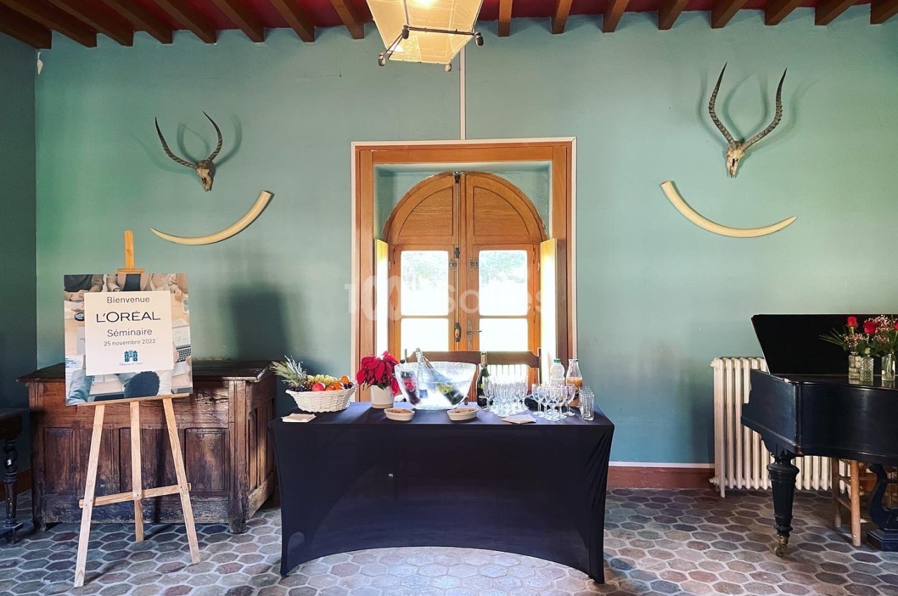 Table dressée avec des collations et boissons dans une salle décorée de bois, trophées muraux et un piano noir.