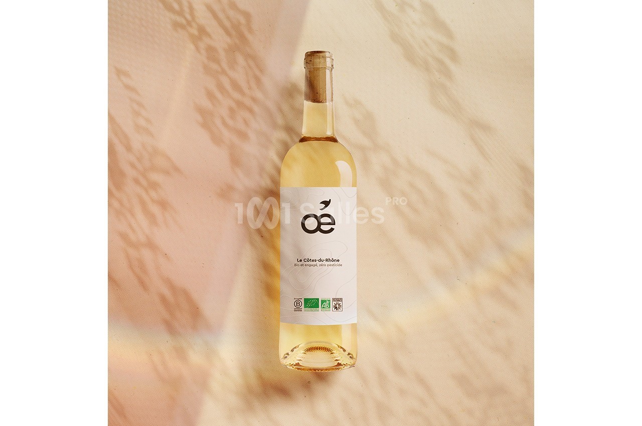 Bouteille de vin blanc bio posée sur une surface beige avec des ombres et reflets lumineux.