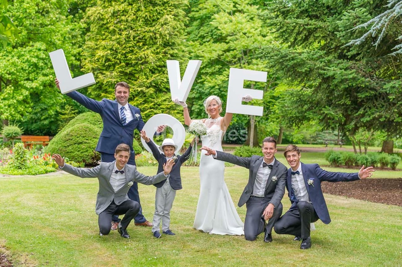 Un groupe de personnes posant dans un jardin, tenant des lettres formant le mot ’LOVE’.