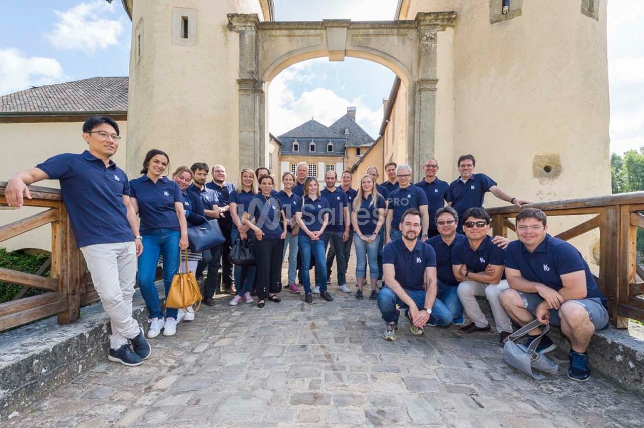 Un groupe de personnes posant devant un bâtiment historique avec une arche en pierre et un pont en bois.