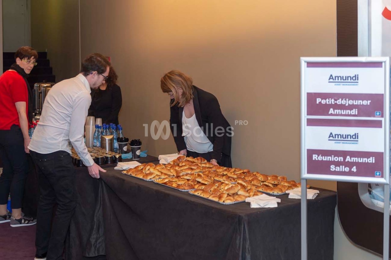 Table avec viennoiseries, boissons et panneaux indiquant ’Petit-déjeuner Amundi’ et ’Réunion Amundi Salle 4’.