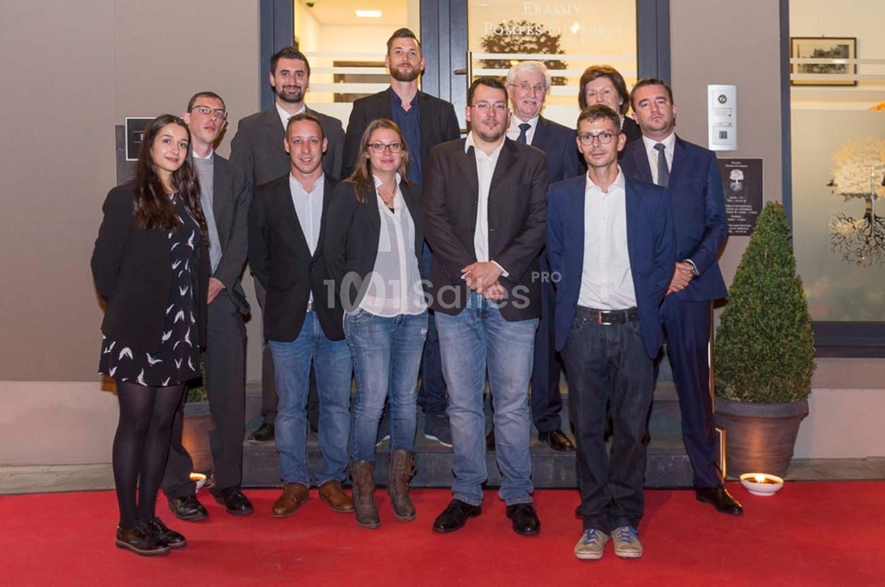 Un groupe de personnes posant sur un tapis rouge devant l'entrée d'un bâtiment.
