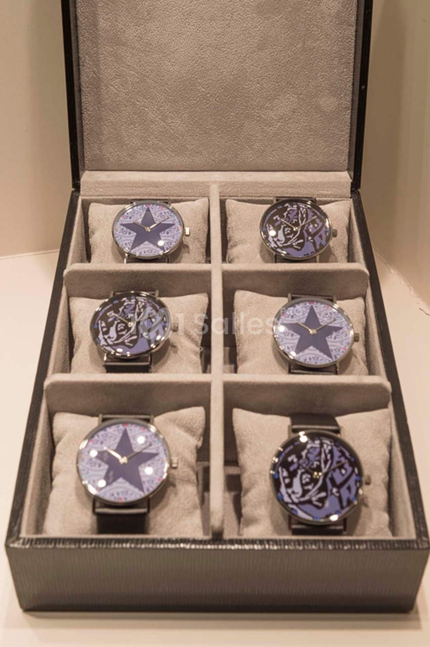 Boîte ouverte contenant six montres-bracelets avec cadrans décorés de motifs étoilés et rangées sur des coussins gris.