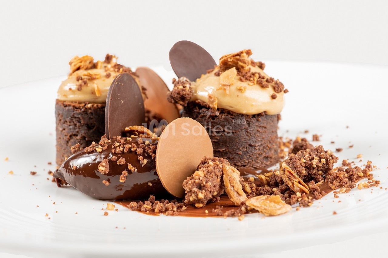 Dessert composé de petits gâteaux au chocolat, mousse au caramel, éclats croustillants et disques de chocolat.