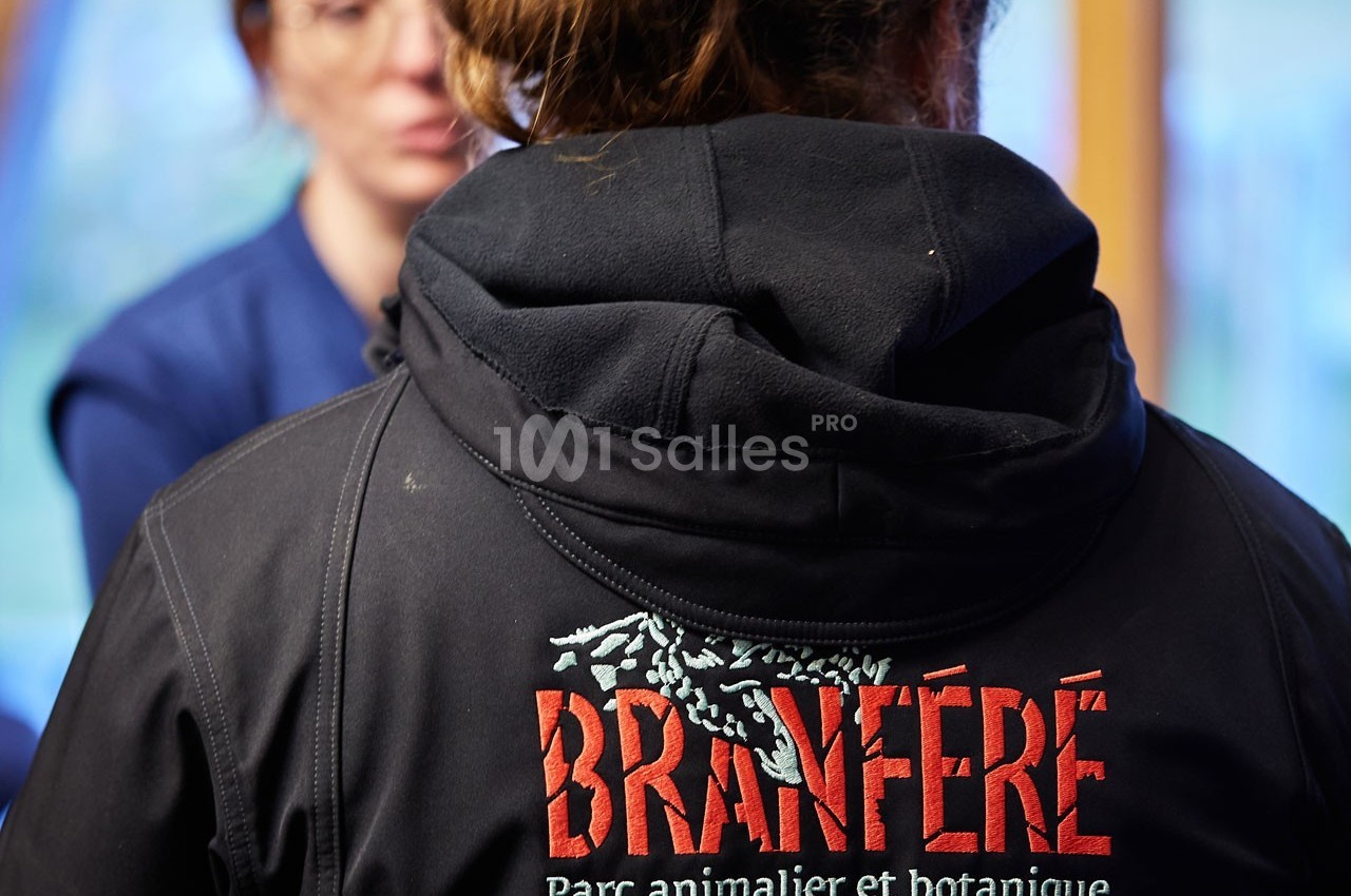 Une personne portant une veste avec le logo ’Branféré, Parc animalier et botanique’, vue de dos.