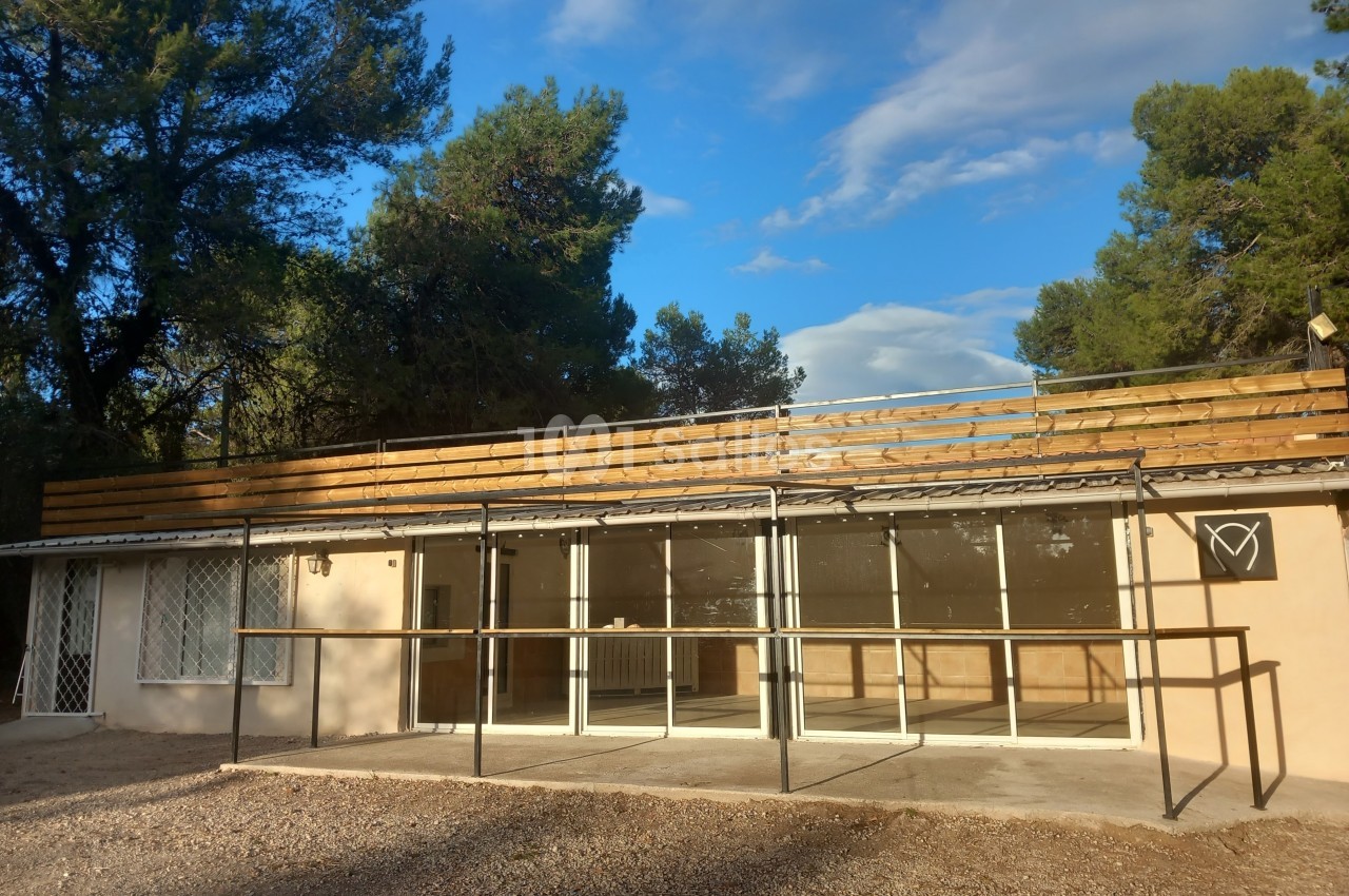 Bâtiment avec façade vitrée, structure métallique et enseigne en forme de cœur, entouré d'arbres sous un ciel dégagé.