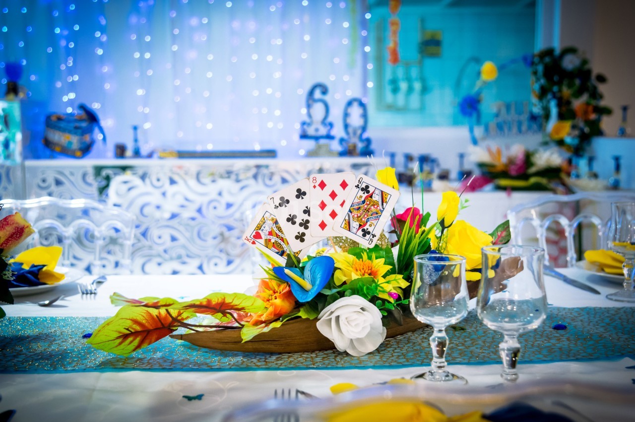 Centre de table coloré avec des fleurs, des cartes à jouer et des éléments décoratifs sur une table dressée.