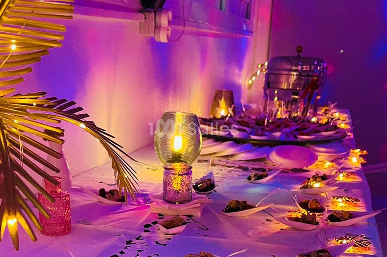 Table décorée avec des lumières colorées, des feuilles tropicales et des amuse-bouches disposés sur des assiettes.