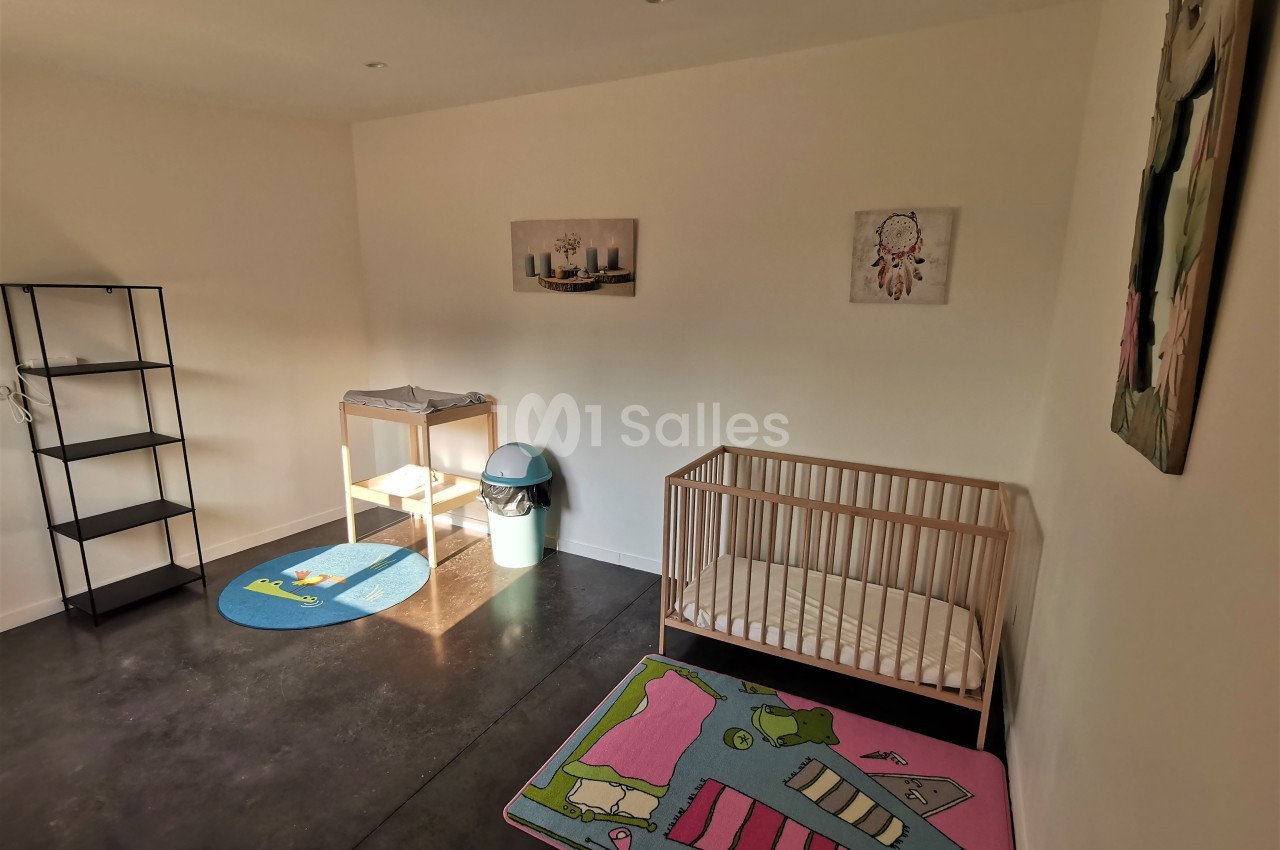 Chambre d'enfant avec un lit à barreaux, une table à langer, des tapis colorés et des décorations murales.