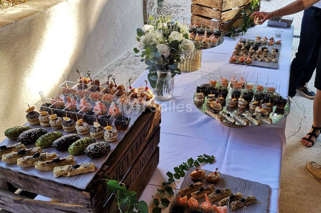 Buffet de pièces cocktail variées disposées sur une table avec décoration florale et caisses en bois.