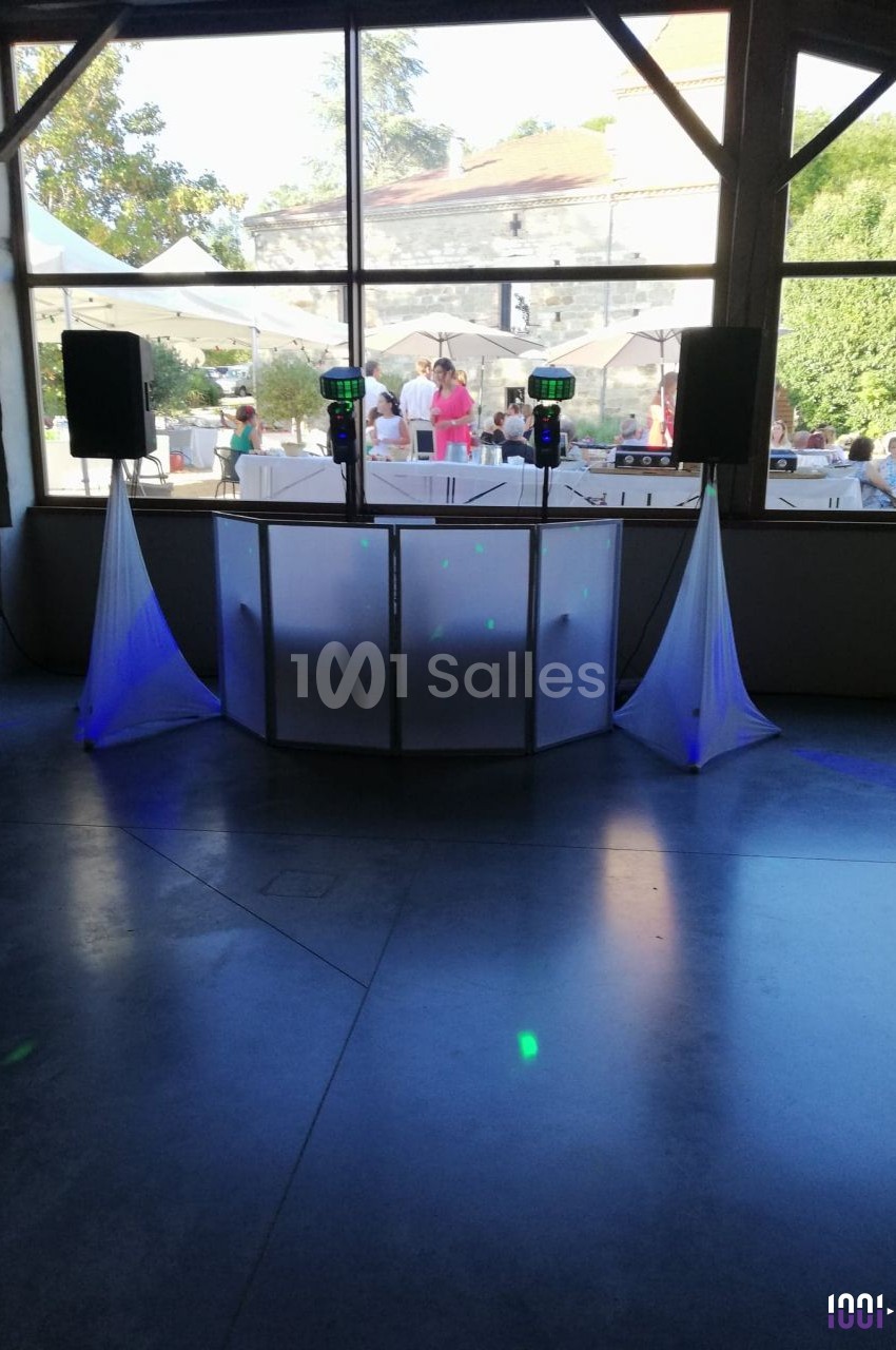 Console de DJ installée en extérieur, entourée de rideaux blancs et éclairée par la lumière naturelle.