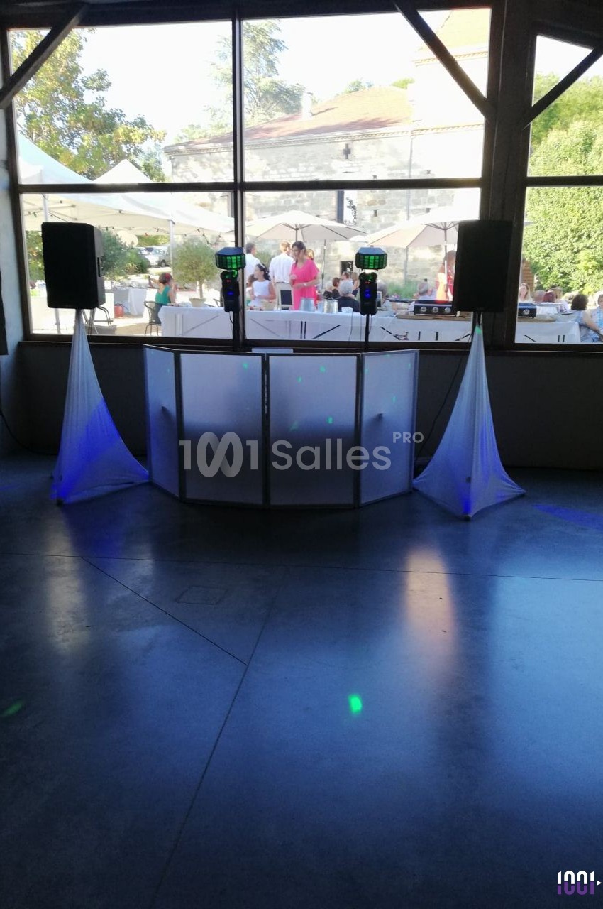 Console de DJ installée en extérieur, entourée de rideaux blancs et éclairée par la lumière naturelle.