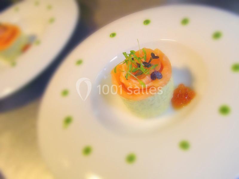 Entrée composée de saumon fumé enroulé autour d'une mousse, garnie de pousses et accompagnée d'une sauce.
