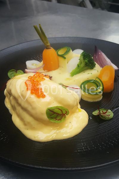 Assiette gastronomique avec poisson nappé de sauce, œufs de poisson, légumes variés et présentation soignée.