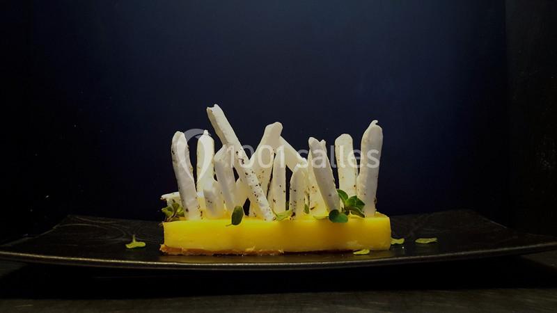 Dessert raffiné composé de bâtonnets blancs dressés sur une base jaune, décoré de micro-pousses.