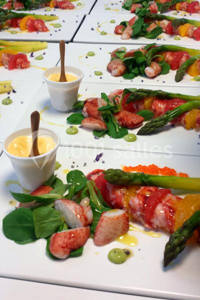 Assiette gastronomique avec homard, asperges, salade, œufs de poisson et sauce servie en verrine.