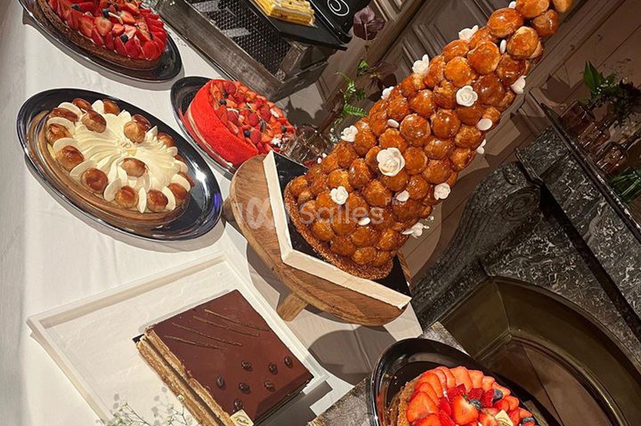 Buffet de desserts comprenant une pièce montée, des tartes aux fruits, un gâteau au chocolat et des choux à la crème.