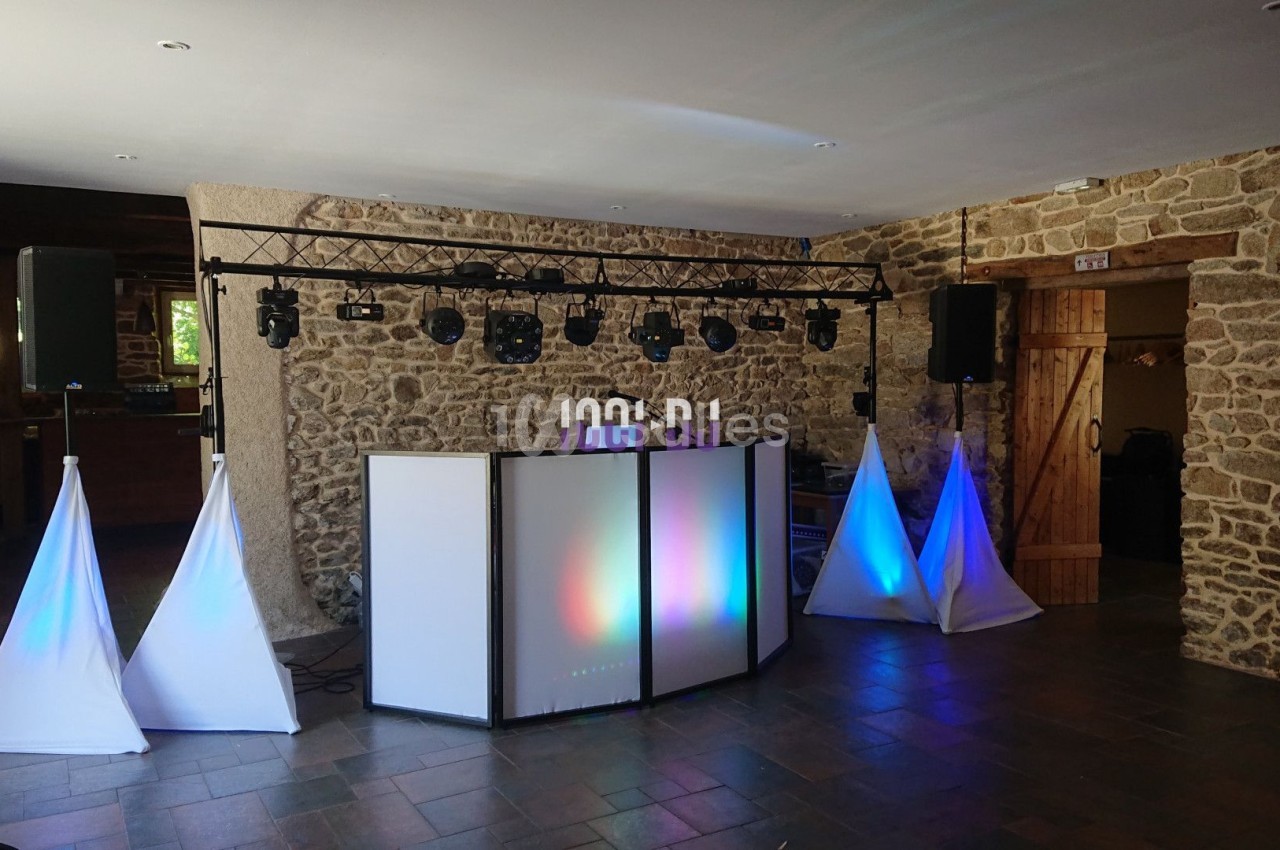 Installation de matériel de sonorisation et d'éclairage dans une salle en pierre avec des spots lumineux colorés.