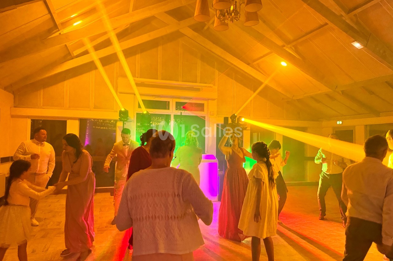 Des personnes dansent dans une salle éclairée par des lumières colorées, créant une ambiance festive.