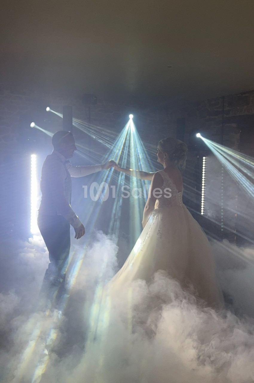 Un couple danse dans une ambiance lumineuse avec des faisceaux lumineux et un sol recouvert de fumée.