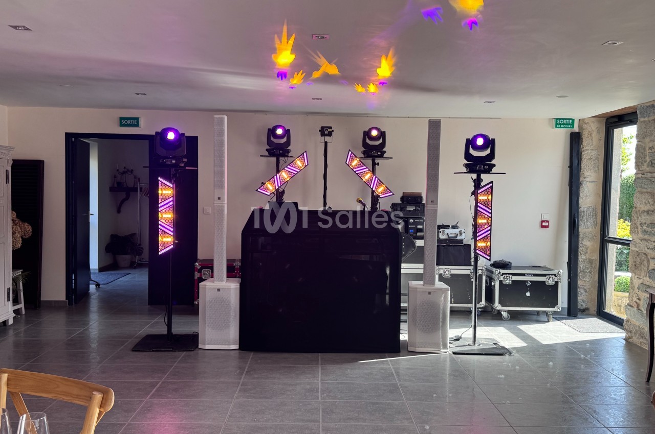 Installation de matériel de sonorisation et d'éclairage avec projecteurs colorés dans une salle lumineuse.
