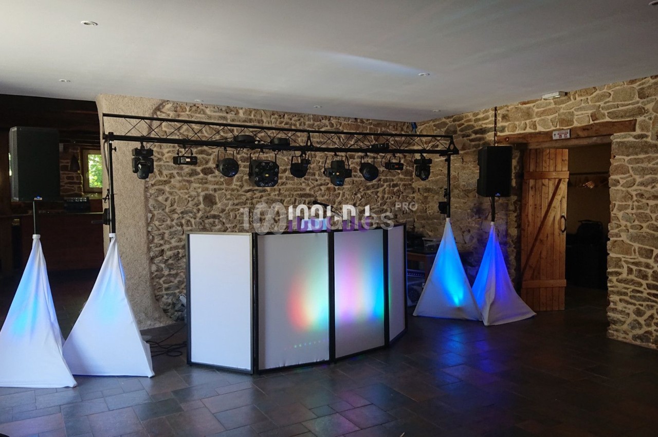 Installation de matériel de sonorisation et d'éclairage dans une salle en pierre avec des spots lumineux colorés.